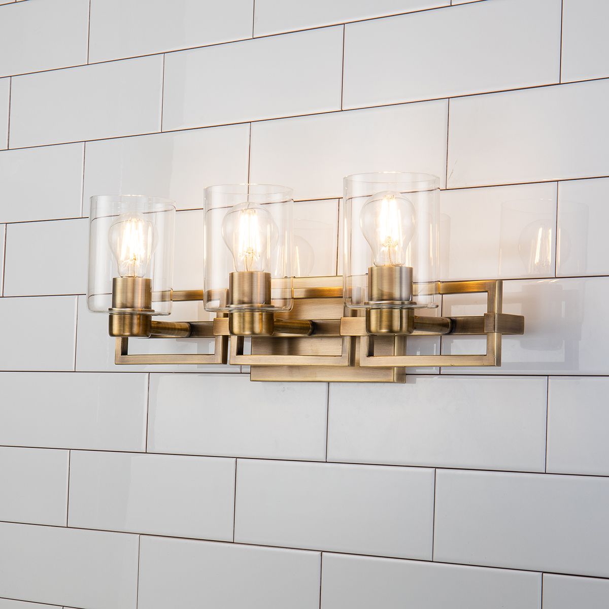 Lucas & McKearn Estes 3-Light Antique Brass Wall Light With Cylinder Shape Clear Glass Shade